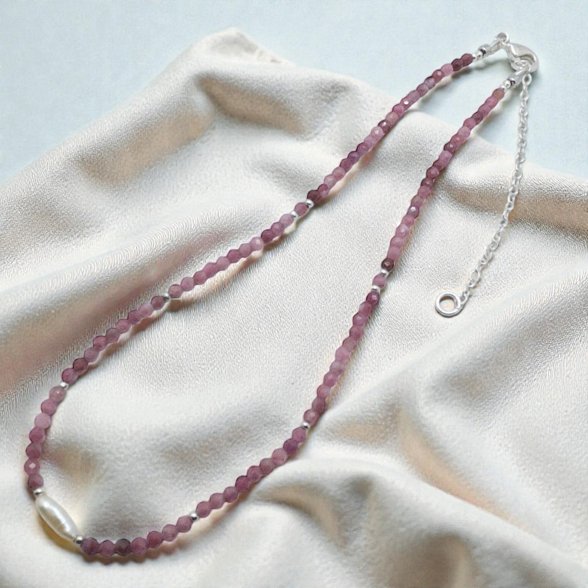 Necklace with pink beads on a white fabric background
