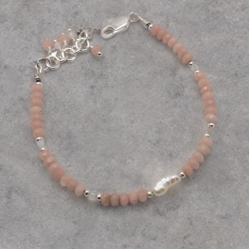 Bracelet is made with faceted oval rondelle beads and separated with moonstone and silver spacer beads.  It features a rice pearl focal and the extender chain adorned with beaded dangles can be used to accommodate a variety of wrist sizes