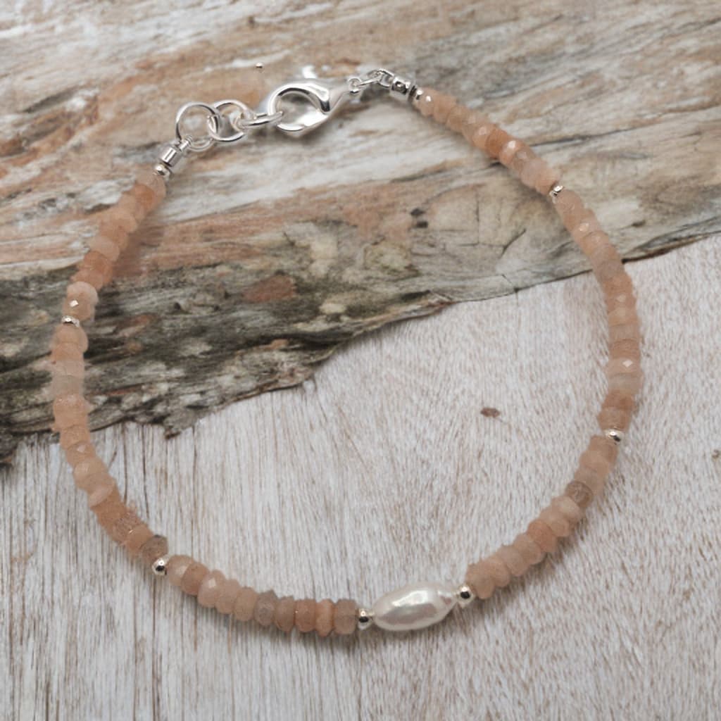 This bracelet is made with faceted rondelle shaped peach moonstone separated with sterling silver spacer beads. The focal is a rice pearl.  It is competed with a sterling silver lobster clasp.