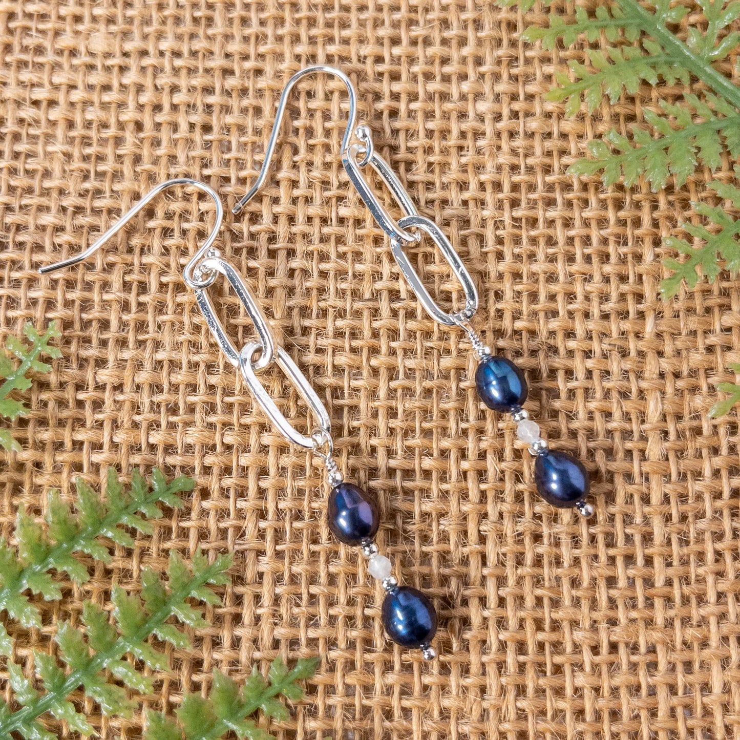 These earrings are approximately 2 inches in length. Iris colored pearls and moonstone gemstones hang from paper clip chain links and include sterling silver ear wires