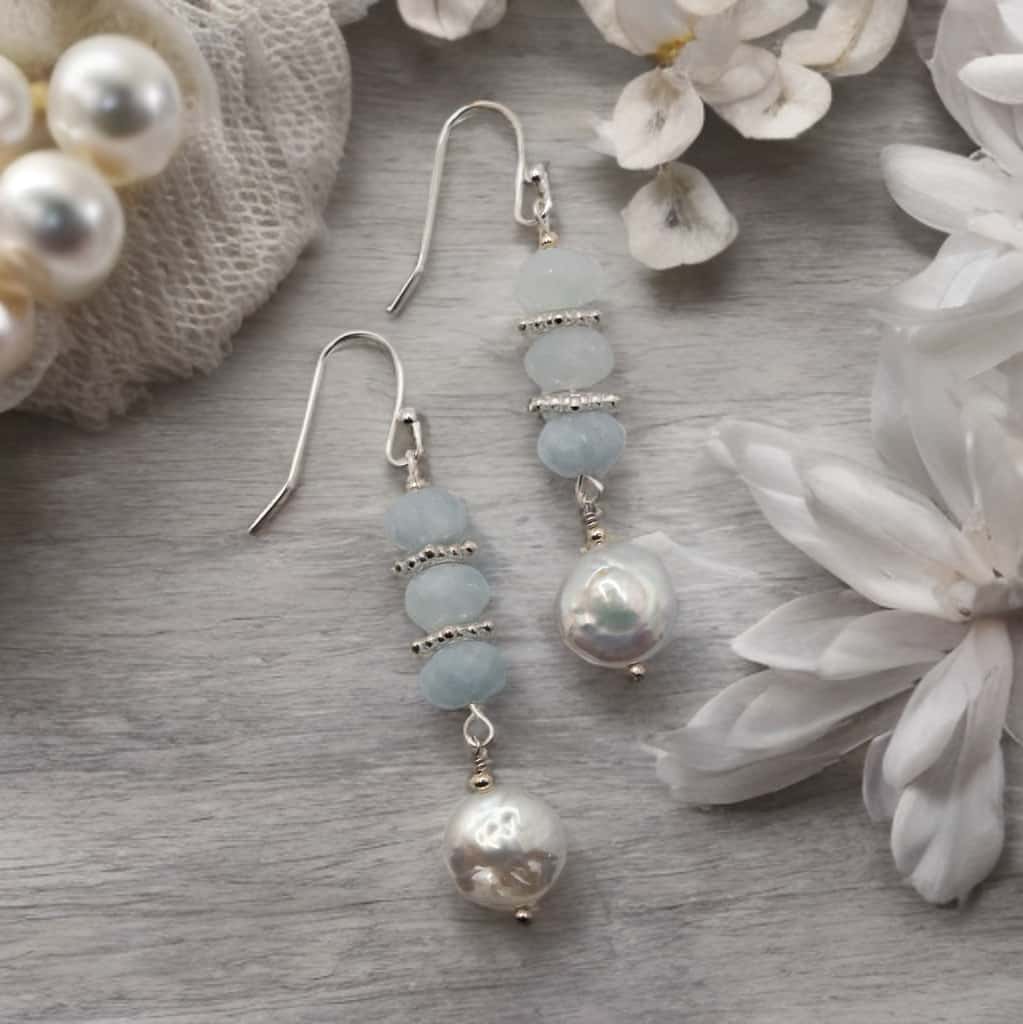 Rondelle shaped aquamarine beads hang from sterling silver ear wires and are accented with coin shaped fresh water pearls.