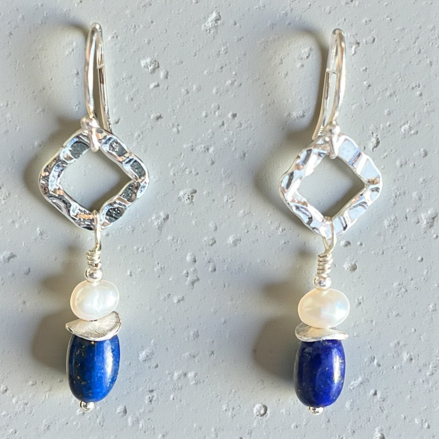 Pair of silver earrings with blue and white beads on a gray background