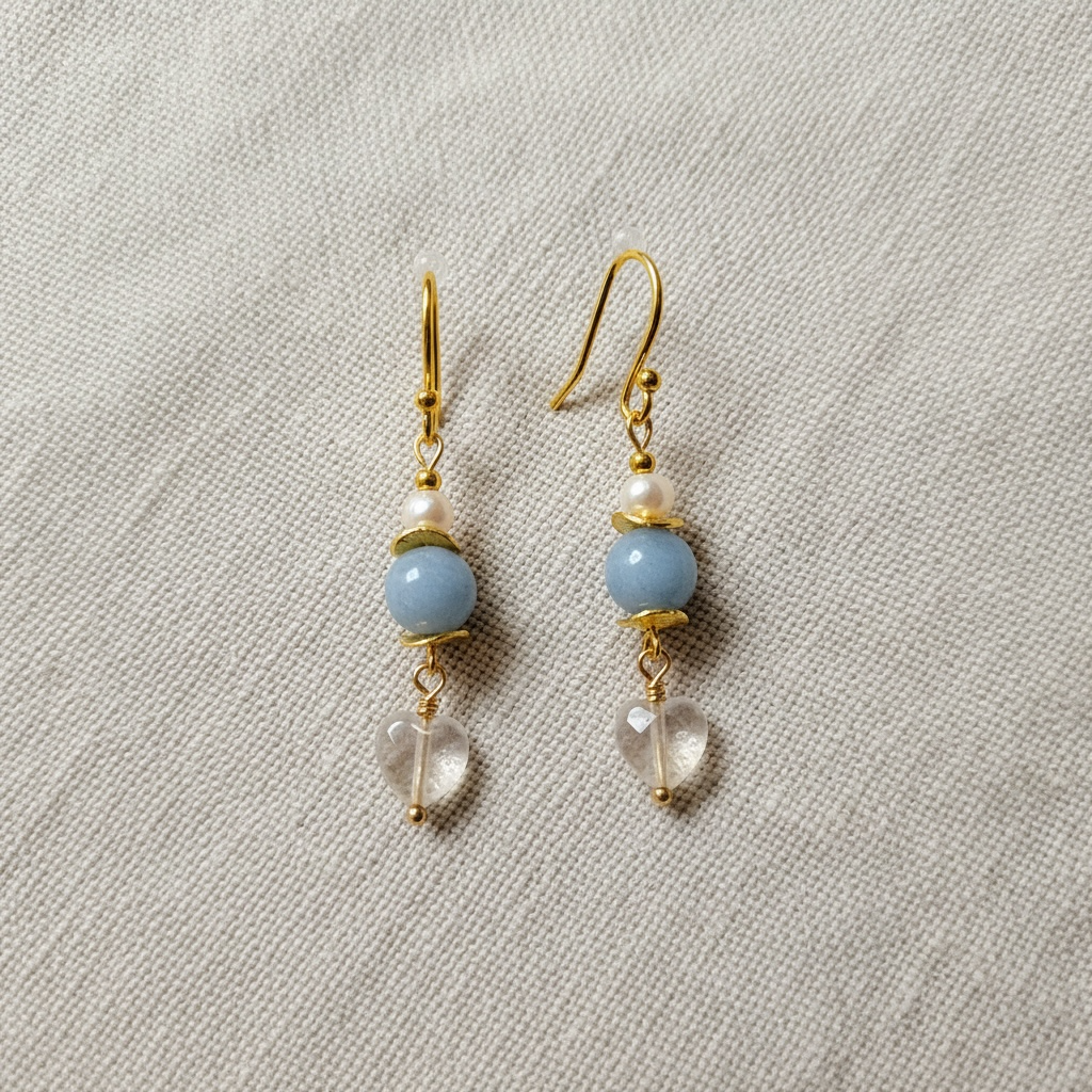 Pair of earrings with blue beads and gold accents on a light gray background