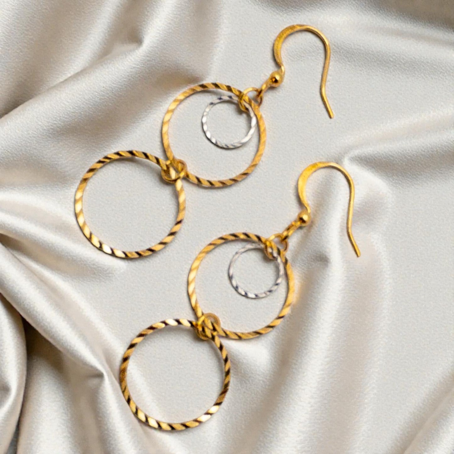 Gold hoop earrings on a satin surface