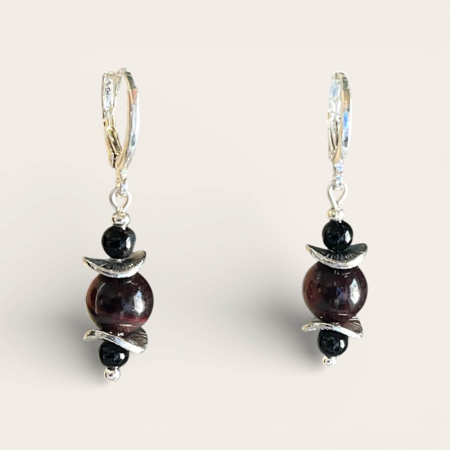 Pair of earrings with dark beads and silver accents on a light background