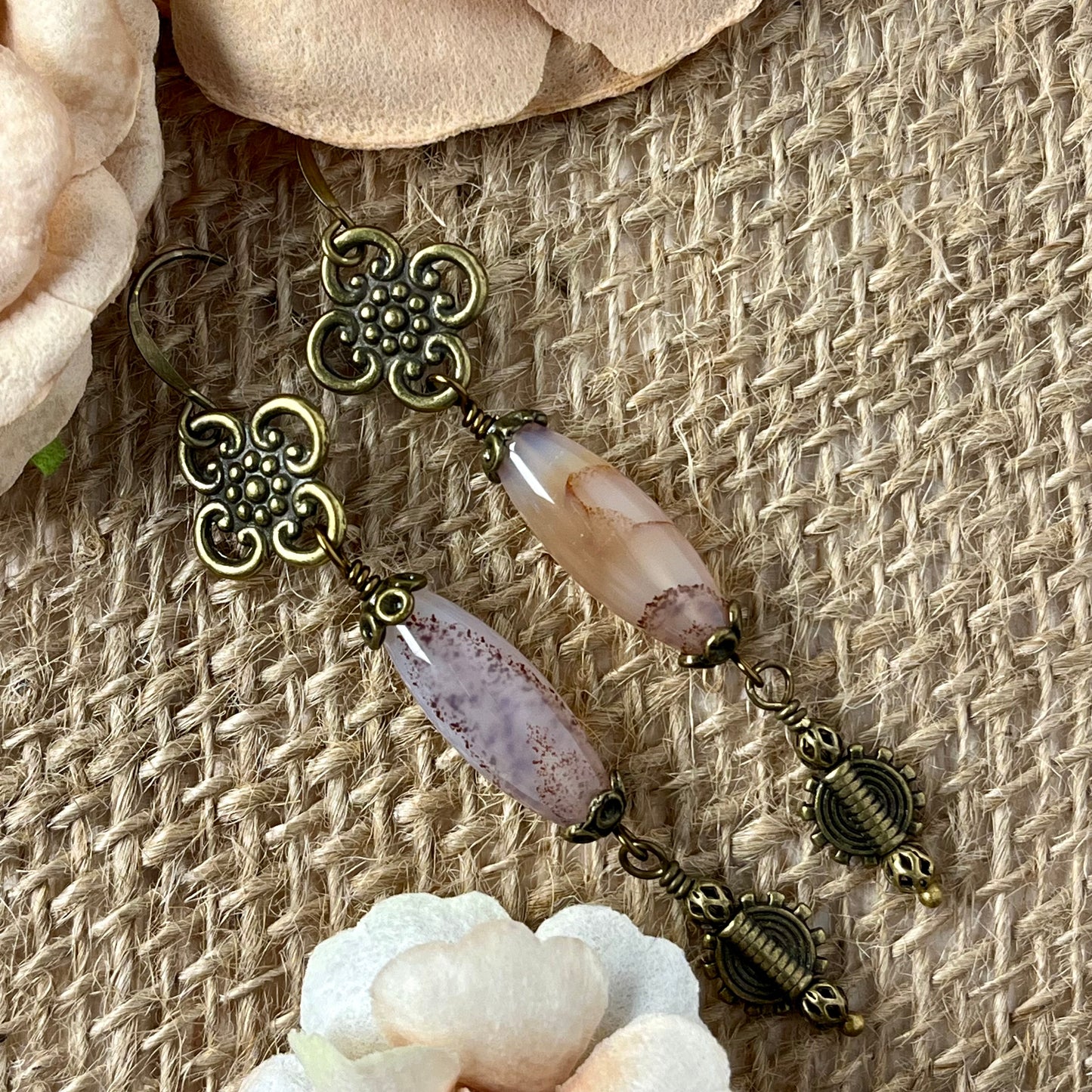 These are earrings made with Carnelian barrel beads. The beads hang from antique bronze metal flower petals and are accented with antique bronze metal beads