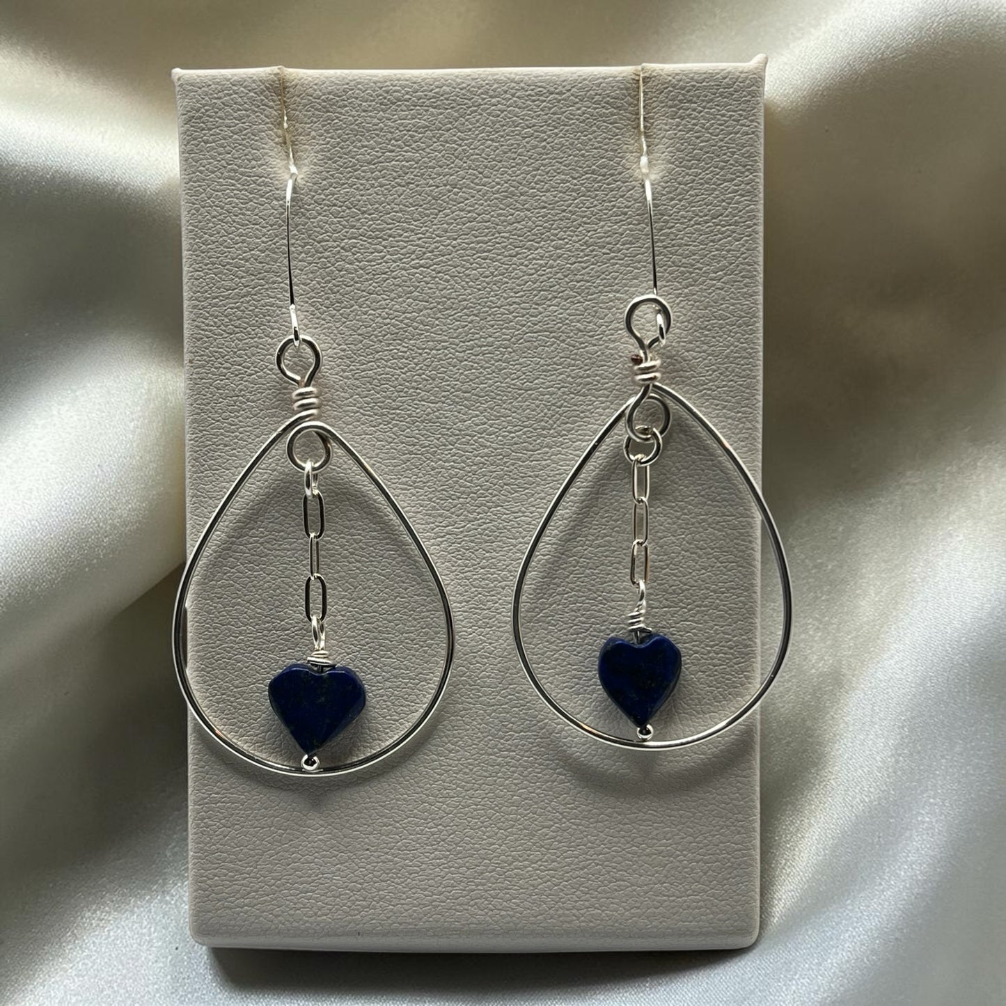 Blakeley Lane Jewelry handcrafted sterling silver teardrop earrings with blue lapis lazuli heart charms on display.