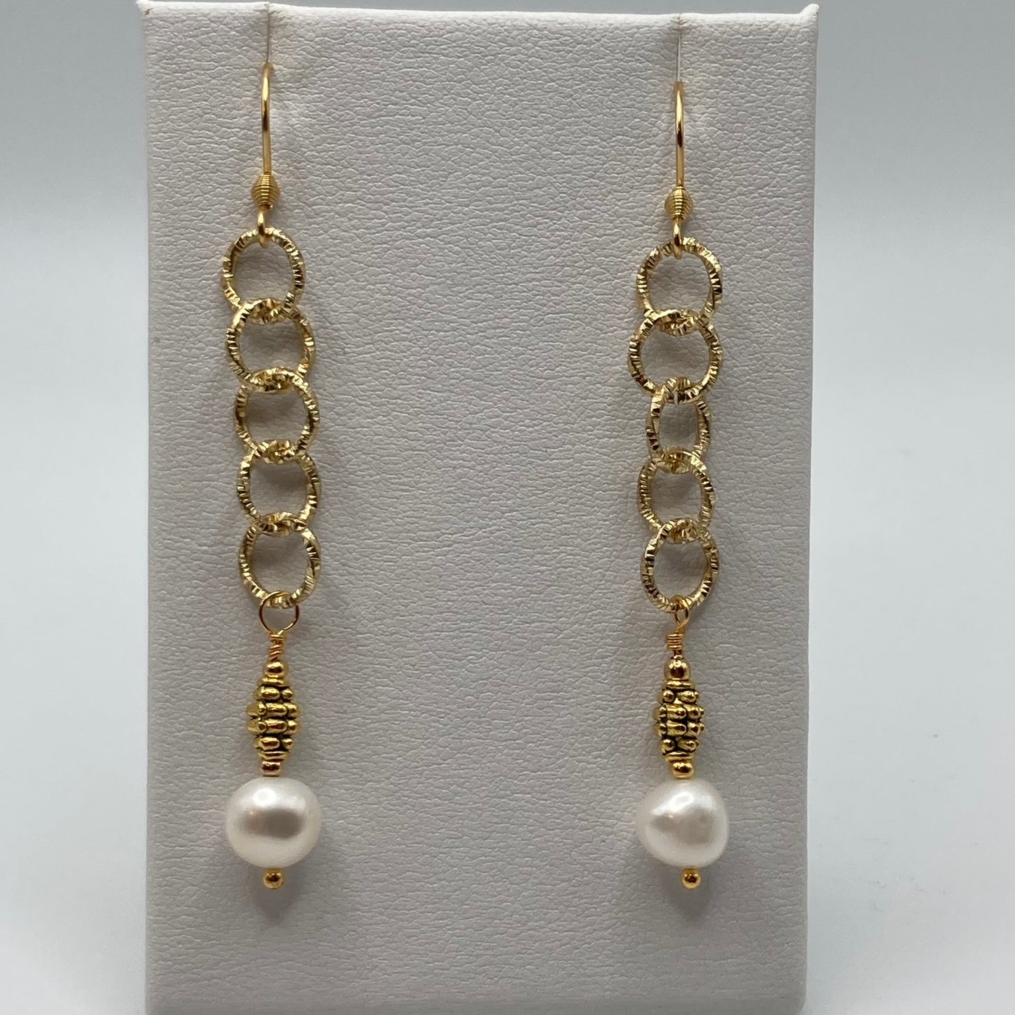 These earrings are made with a freshwater pearl dangle which is attached to gold-tone chain. They measure approximately one inch in length.