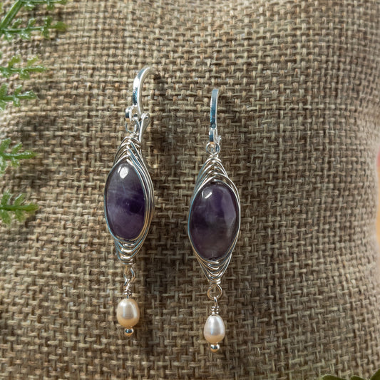 Measuring approximately 1.5 inches in length, each earring features a herringbone weave wrapped amethyst bead and a delicate rice pearl dangle. Enhance your natural energy and style with these simple yet lovely earrings.