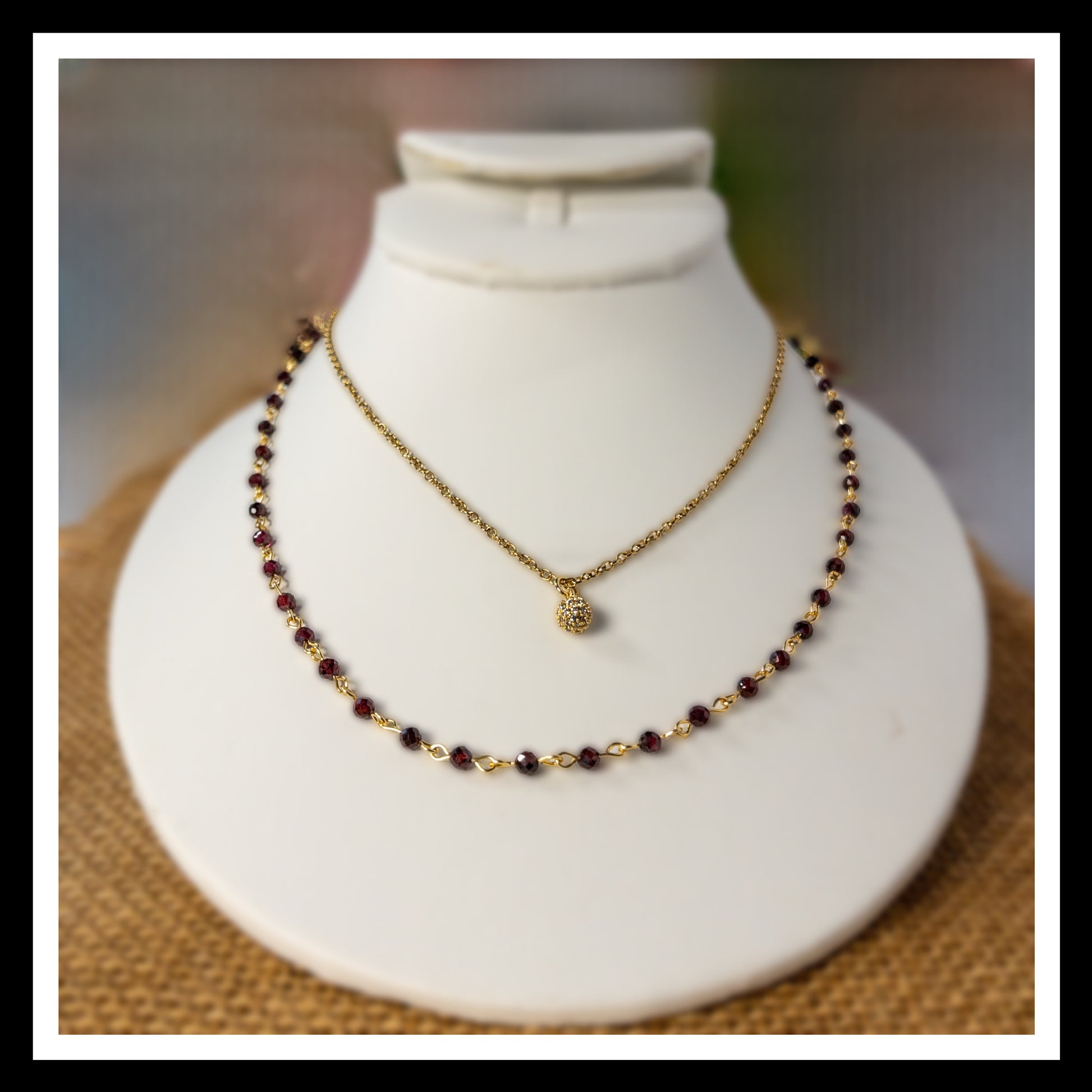 The beaded garnet chain is shown layered with a single gold chain necklace that includes a pave crystal bead.
