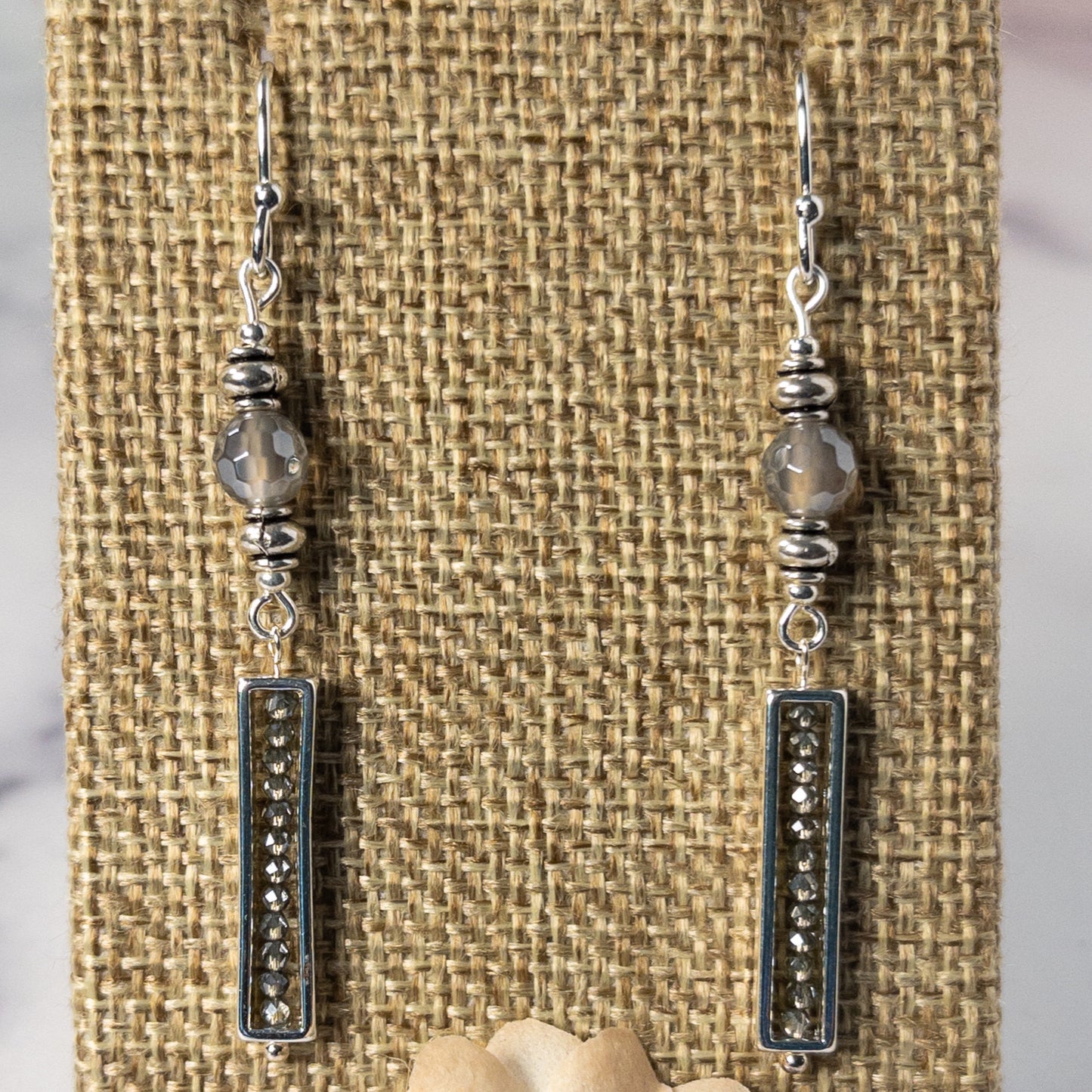 These stunning earrings feature smokey quartz and silver luster beads, with delicate diamond accents enclosed in silver frames. With a length of approximately 2 inches, these earrings are the perfect statement piece to add to any outfit.