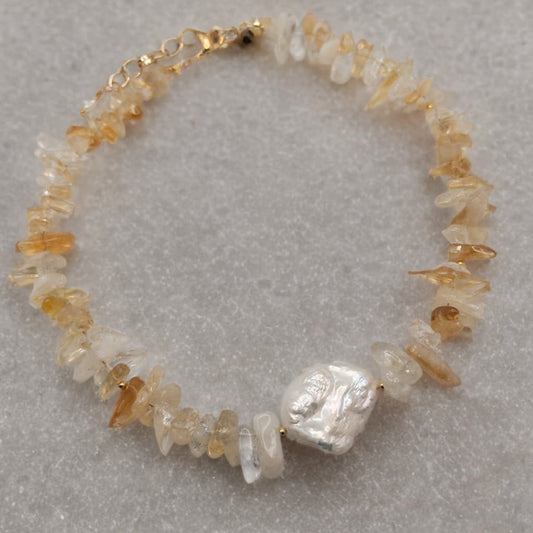 This necklace is made with citrine chip beads and highlighted by a baroque pearl focal.  The spacer beads and clasp are gold tone.

