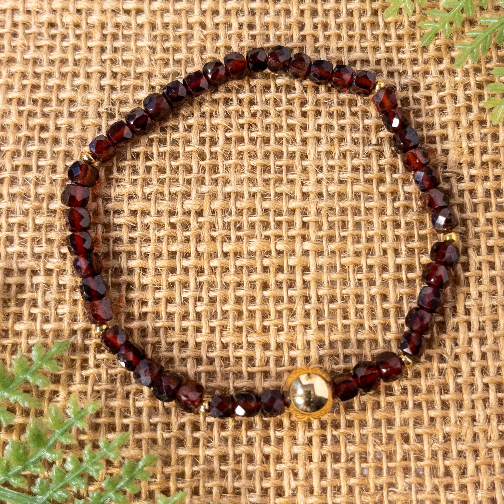 This is a stretch bracelet made with cube shaped faceted garnet beads.  It include round gold spacer beads and an 8mm gold plated focal bead.
