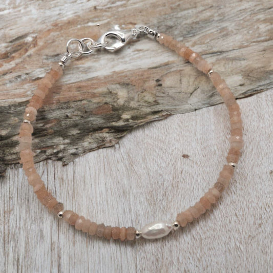 This bracelet is made with faceted rondelle shaped peach moonstone separated with sterling silver spacer beads. The focal is a rice pearl.  It is competed with a sterling silver lobster clasp.
