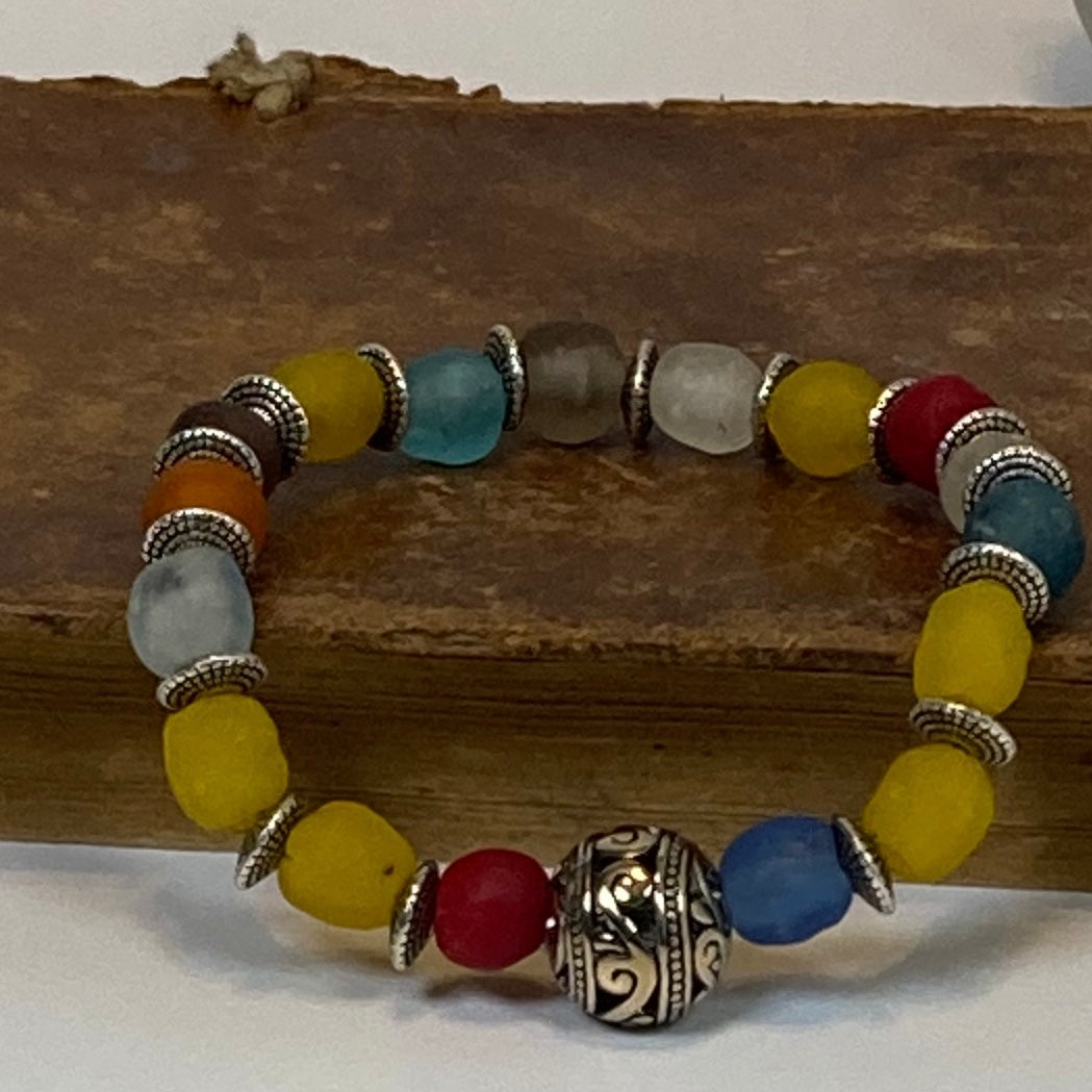 Handcrafted with multicolor recycled glass beads.  It features and Indonesian inspired metal focal bead and saucer shaped metal spacer beads