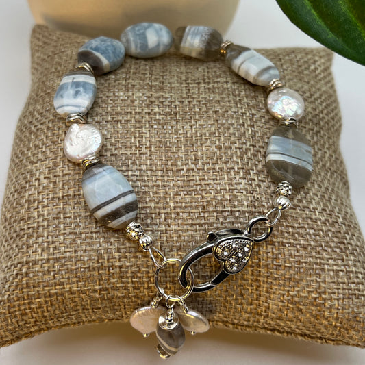 This is a 7.25 inch bracelet made with banded opal blue banded opal and gray chalcedony and coin pearls.  It includes a large lobster clasp that is adorned with bead and coin pearl dangles