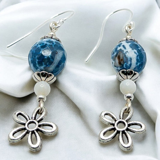 Pair of earrings with blue and white bead and silver flower charm on a white background