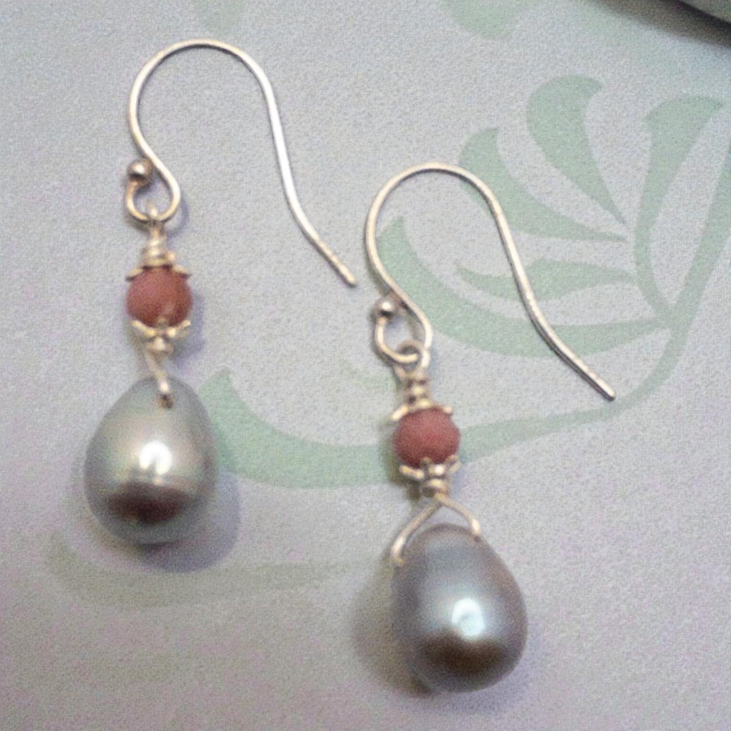 Pair of earrings with gray freshwater pearls  pearls and pink rhodonite beads on a light background