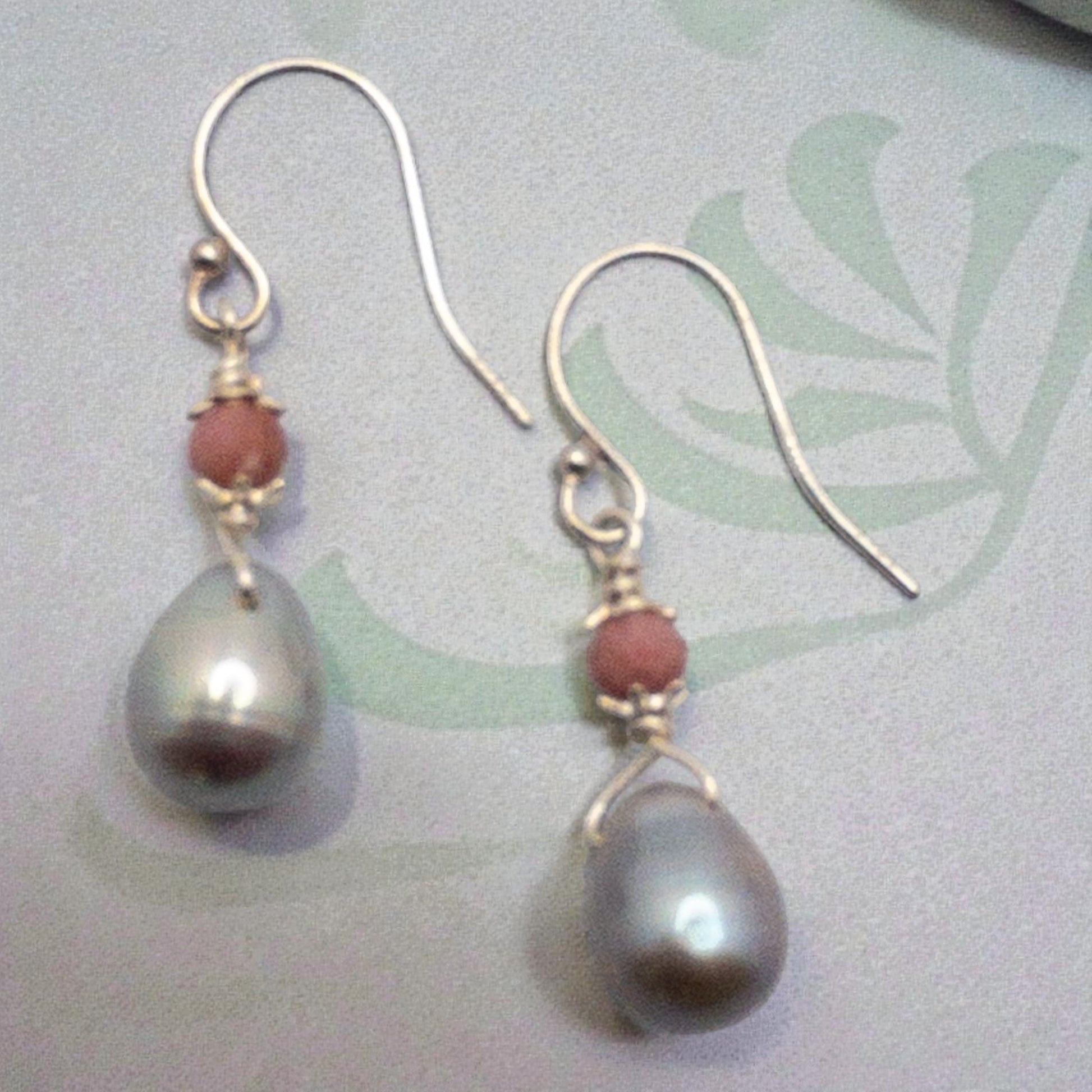 Pair of earrings with gray freshwater pearls  pearls and pink rhodonite beads on a light background