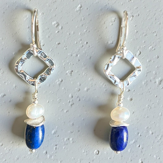 Pair of silver earrings with blue and white beads on a gray background