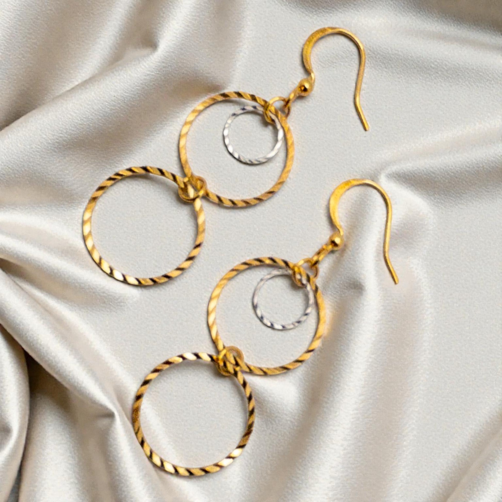 Gold hoop earrings on a satin surface