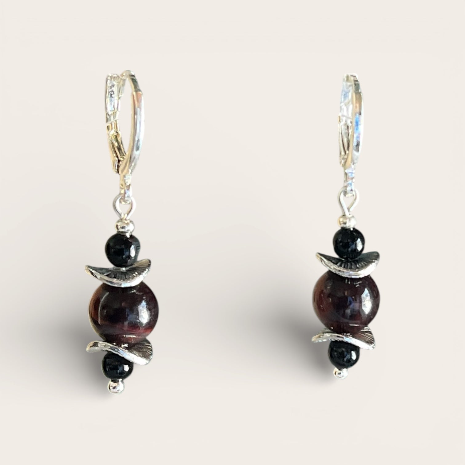Pair of earrings with dark beads and silver accents on a light background