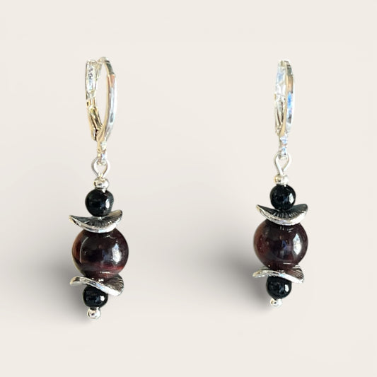 Pair of earrings with dark beads and silver accents on a light background