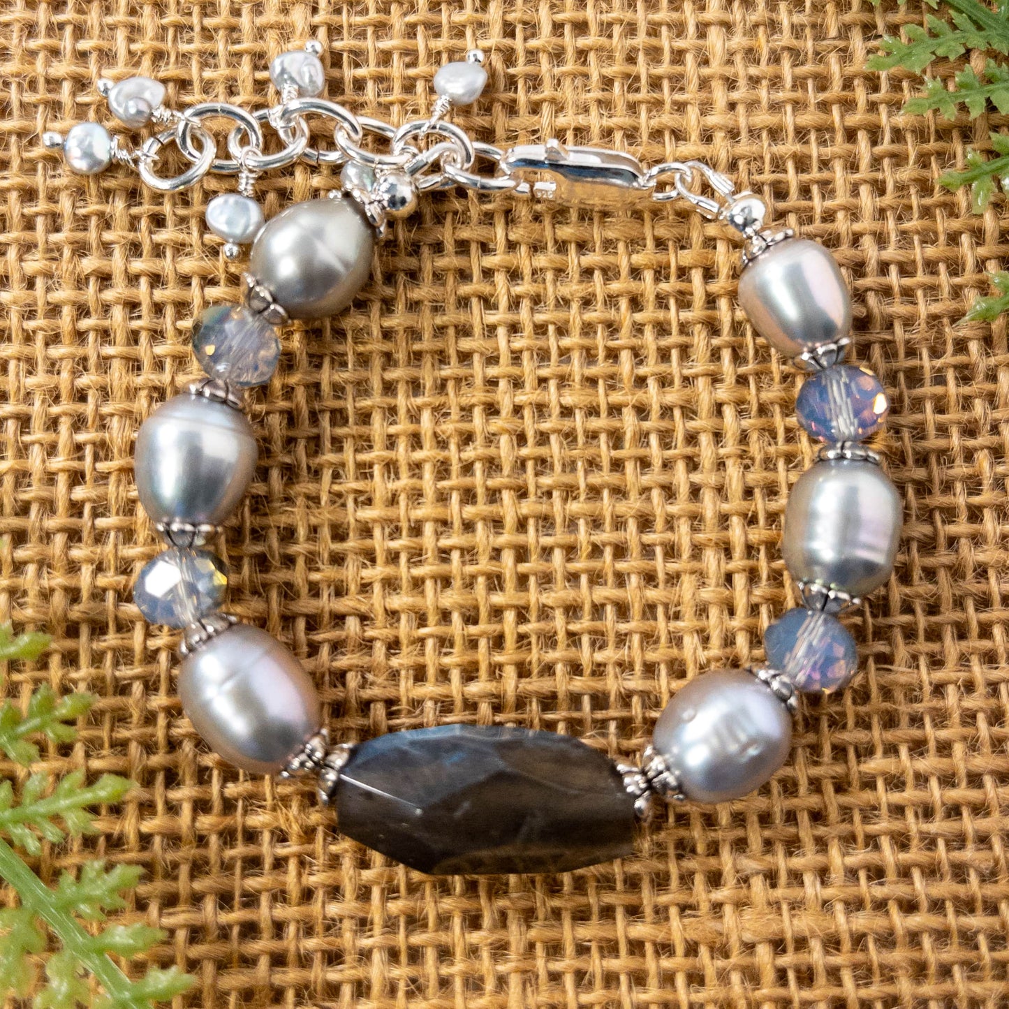 This bracelet features a large faceted labradorite nugget bead that is surrounded by grey pearls and crystals.  It includes an extender adorned with small fresh water beaded dangles. 