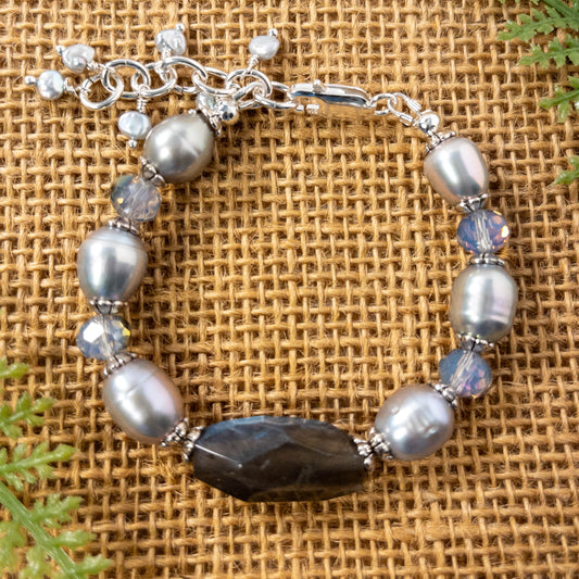 This bracelet features a large faceted labradorite nugget bead that is surrounded by grey pearls and crystals.  It includes an extender adorned with small fresh water beaded dangles. 