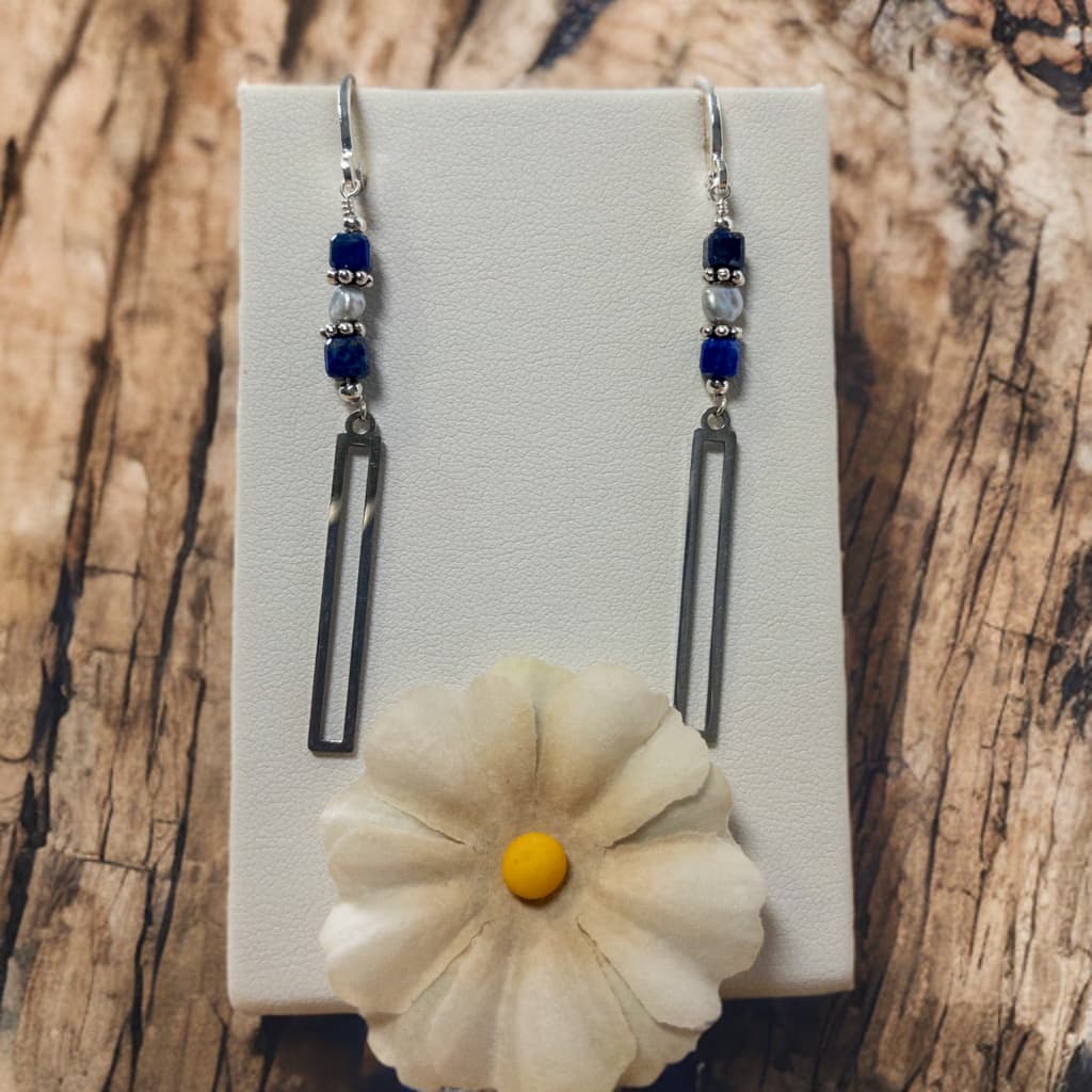 Earrings are approximately  inches in length and are made with lapis cube shaped beads and tiny grey fresh water pearls.  Suspended from the beads is a stainless steel bead frame.