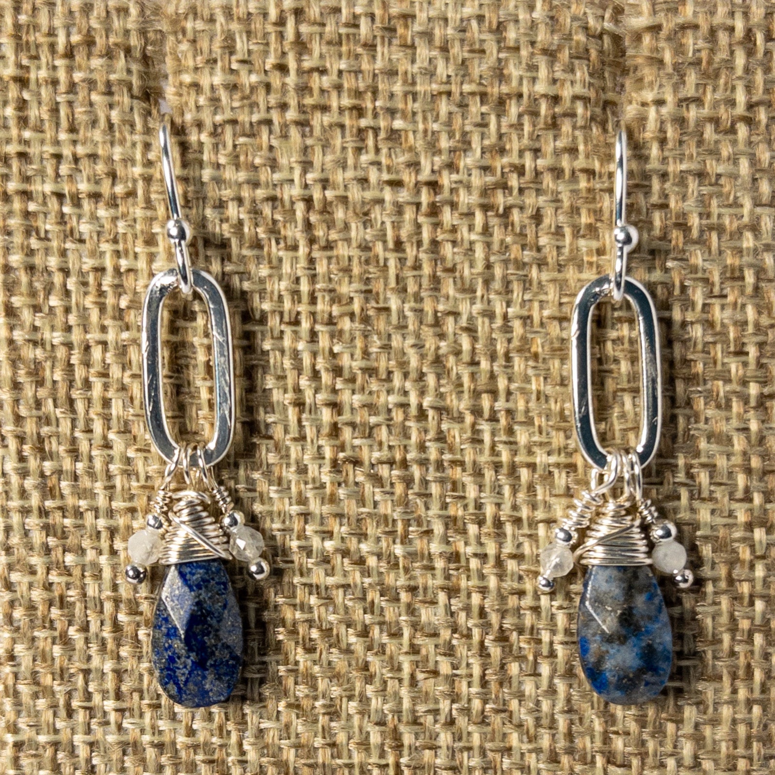 The faceted tear drop shaped beads, suspended from a paperclip chain, add a touch of sophistication. The complementary blue and silver tones enhance the beauty of the lapis, known for its calming and healing properties. Completed with sterling silver ear wires.