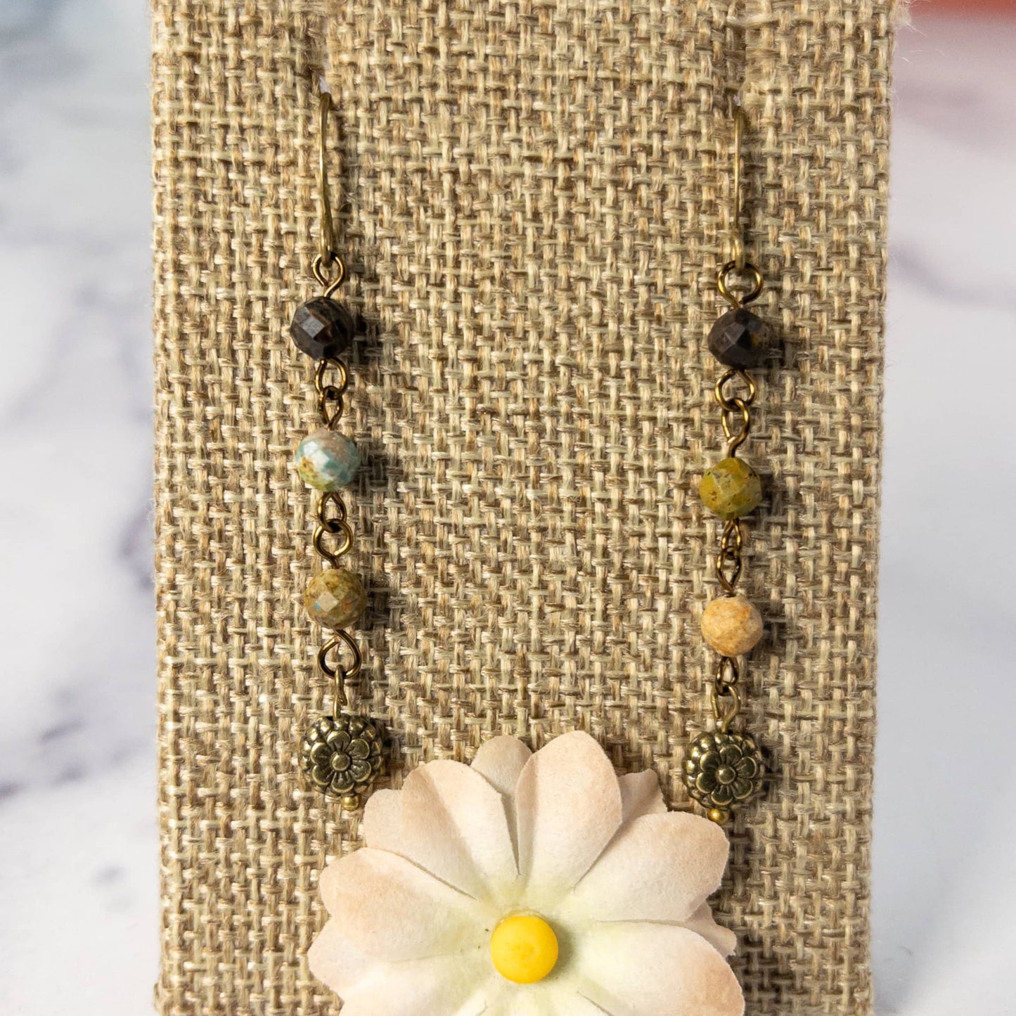  Measuring 1.5 inches in length, these earrings feature a beaded chain made from small faceted turquoise beads and are finished with an antique bronze flower charm. 