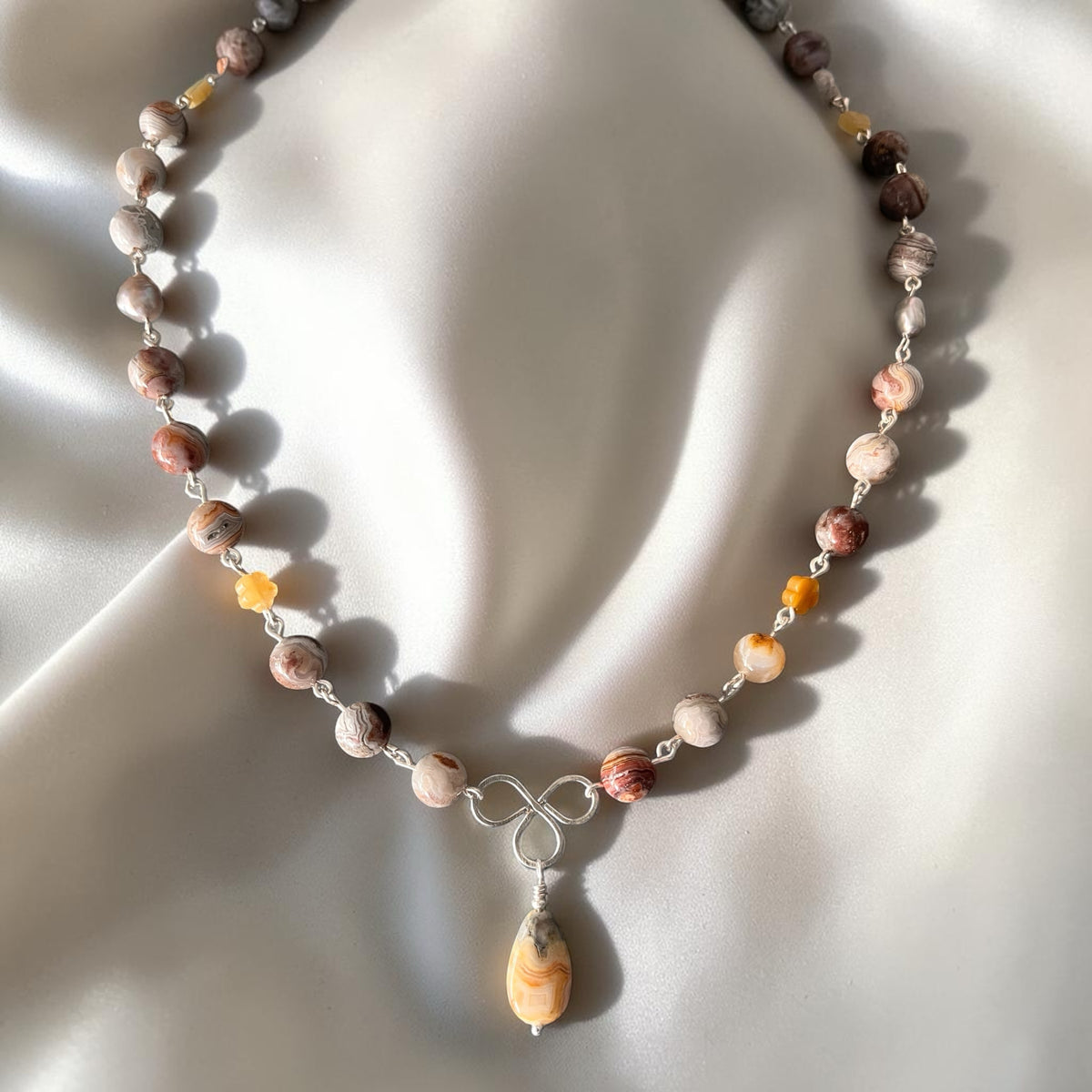 Blakeley Lane Jewelry handcrafted agate beaded necklace with a teardrop pendant and silver infinity knot accent.