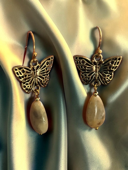 Blakeley Lane Jewelry antique gold filigree butterfly drop earrings with creamy teardrop stones on satin fabric.