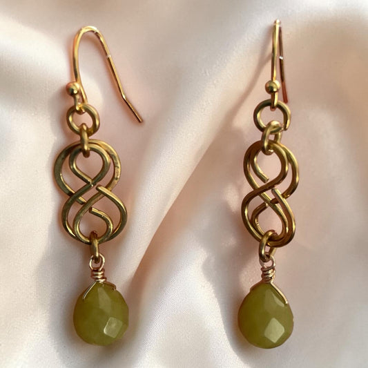 Blakeley Lane Jewelry gold-toned infinity drop earrings with faceted olive-green gemstone pendants on hook backings.