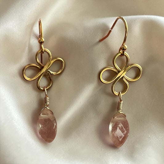 Blakeley Lane Jewelry gold-tone wire-wrapped clover earrings with faceted pink crystal drops on a white silk background