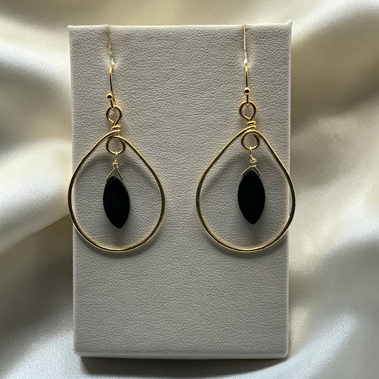 Blakeley Lane Jewelry gold teardrop dangle earrings with black marquise stone and wire-wrapped detail on display.