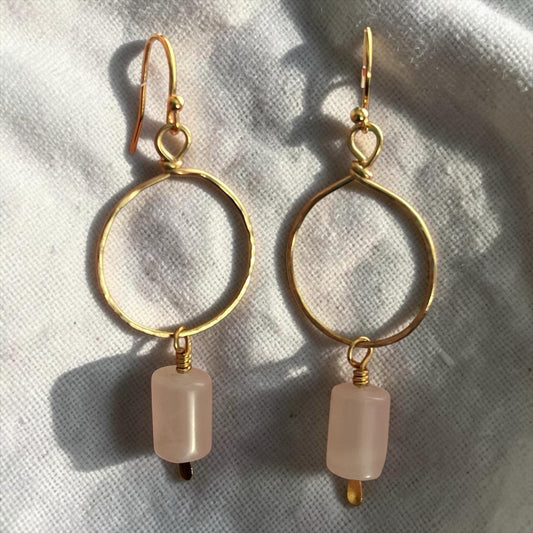 Blakeley Lane Jewelry gold-tone hammered hoop drop earrings with cylindrical rose quartz beads on white fabric.
