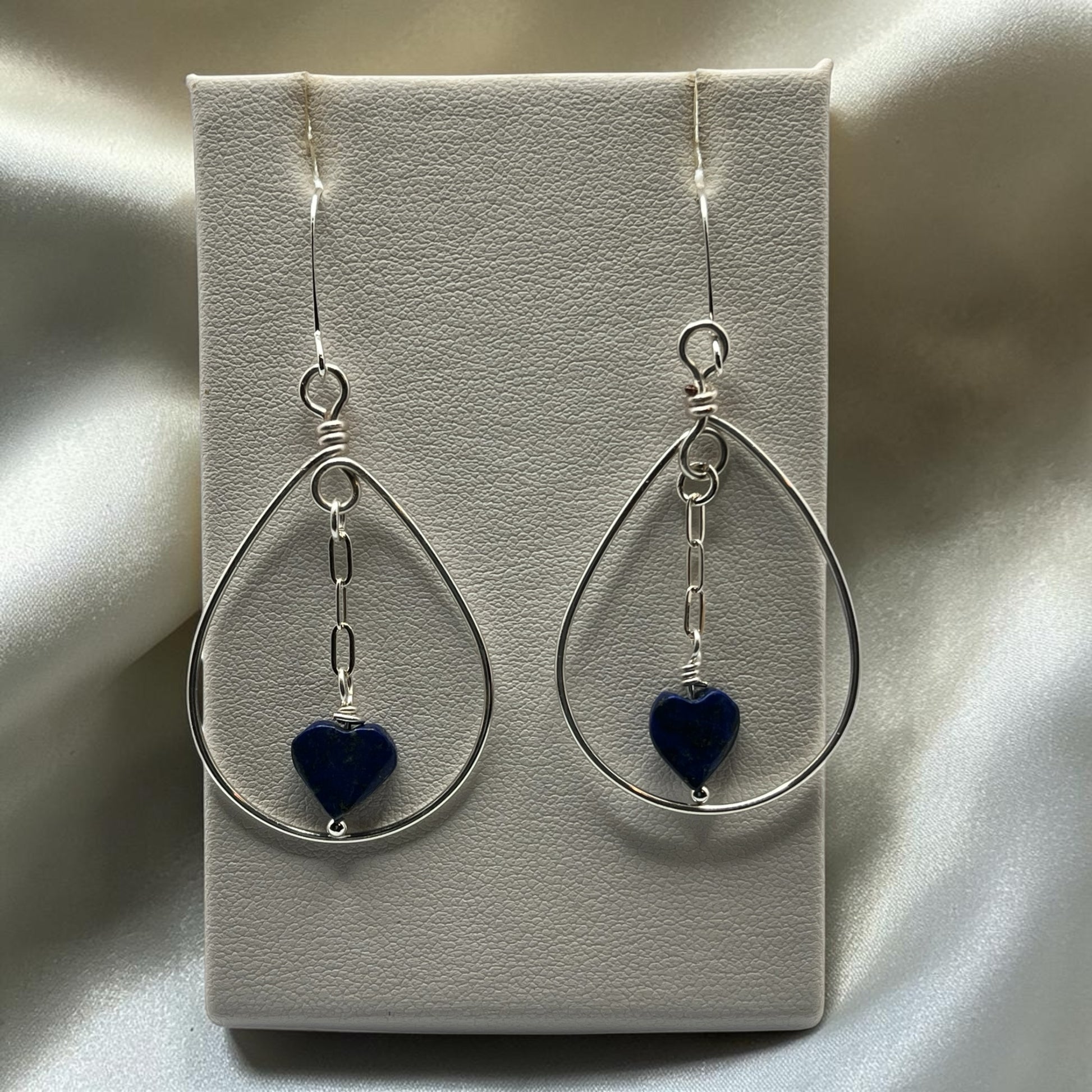 Blakeley Lane Jewelry handcrafted sterling silver teardrop earrings with blue lapis lazuli heart charms on display.
