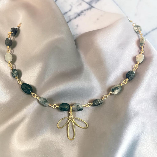 Blakeley Lane Jewelry moss agate beaded necklace with a gold-tone floral charm on a soft grey silk background.