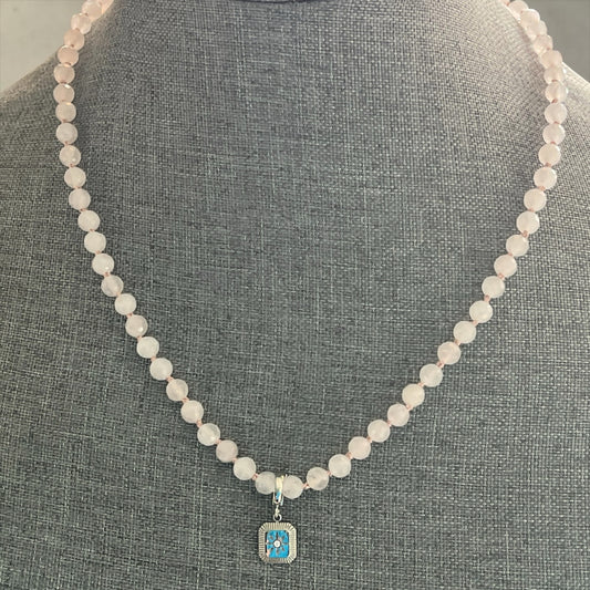 Blakeley Lane Jewelry rose quartz beaded necklace with a rectangular blue enamel and silver pendant on a grey bust.