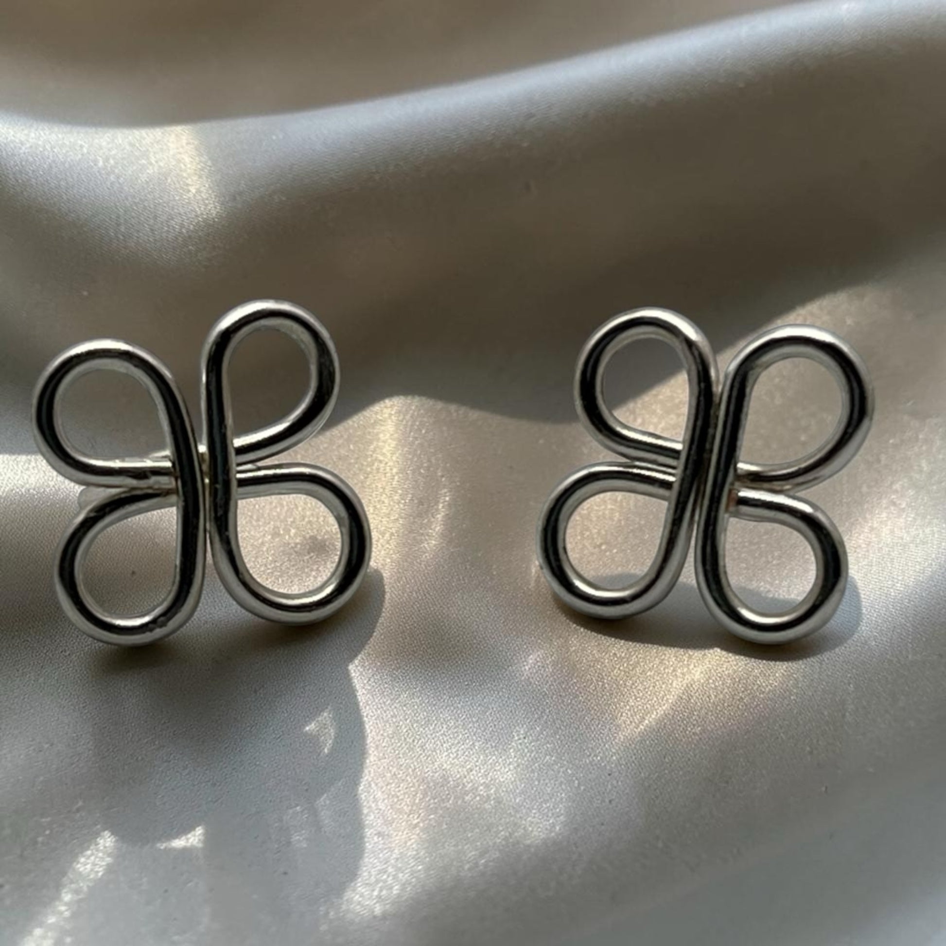 Blakeley Lane Jewelry silver-toned sculptural loop stud earrings with a polished clover-inspired open-work design.