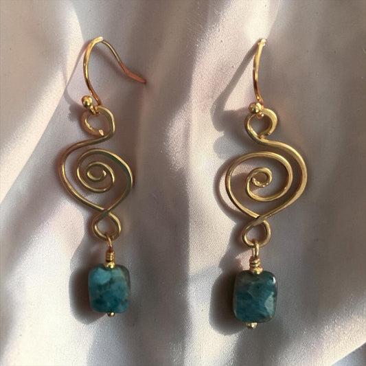 Blakeley Lane Jewelry gold-tone wire spiral drop earrings with faceted blue-green gemstone beads on silk fabric.