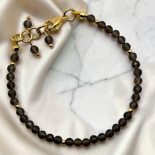 Bracelet with smokey quartz beads and gold accents on a marble surface