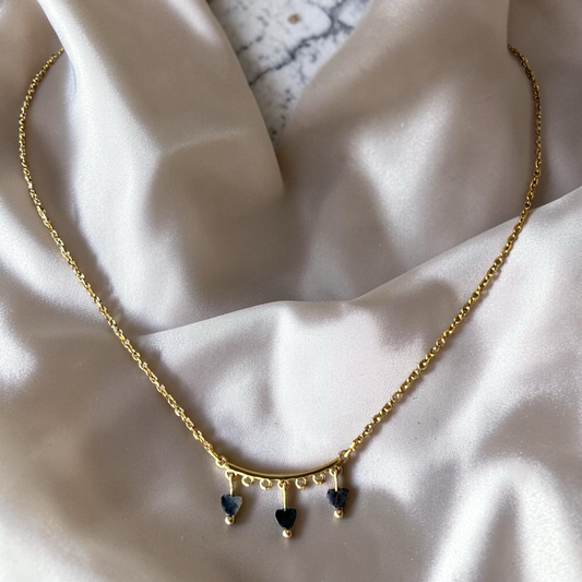 Gold necklace with heart-shaped pendants on a soft fabric background