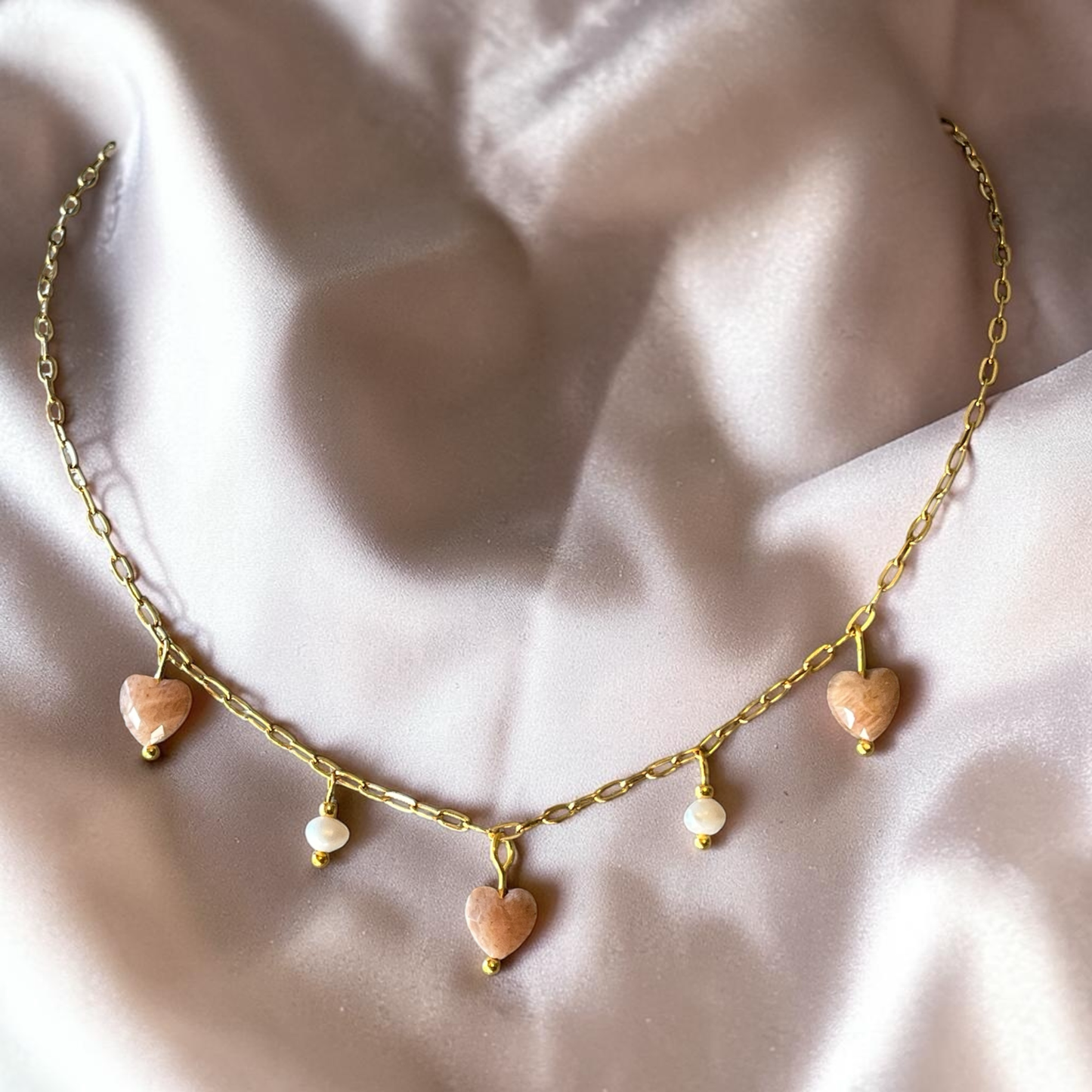 Necklace with heart-shaped pendants on a soft fabric background
