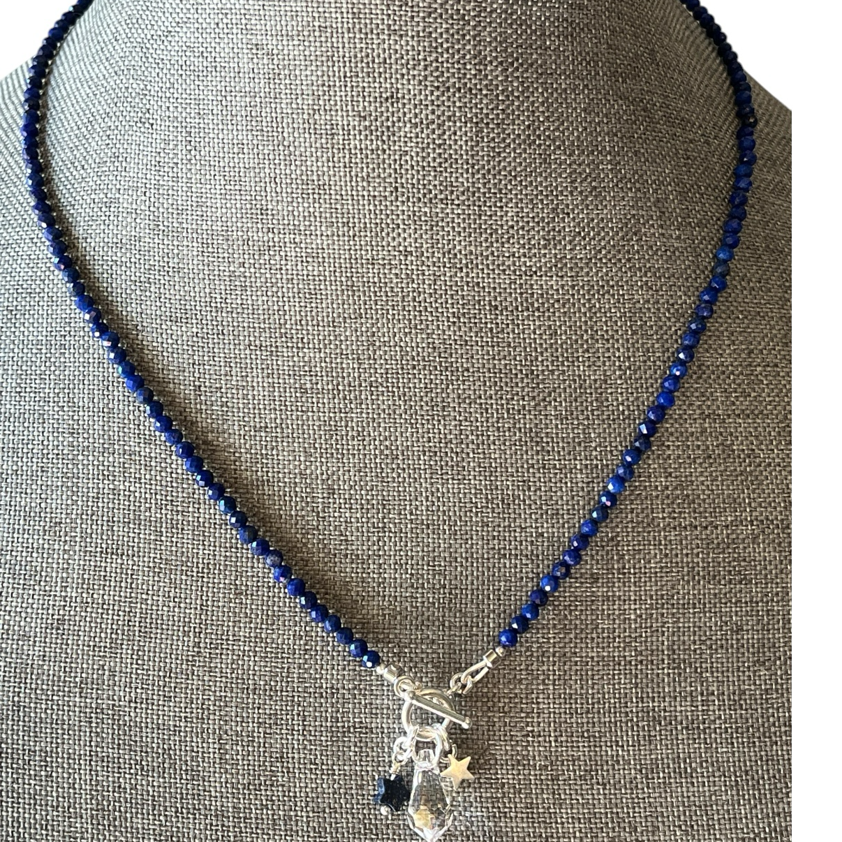 Necklace with blue beads and silver charms on a gray mannequin