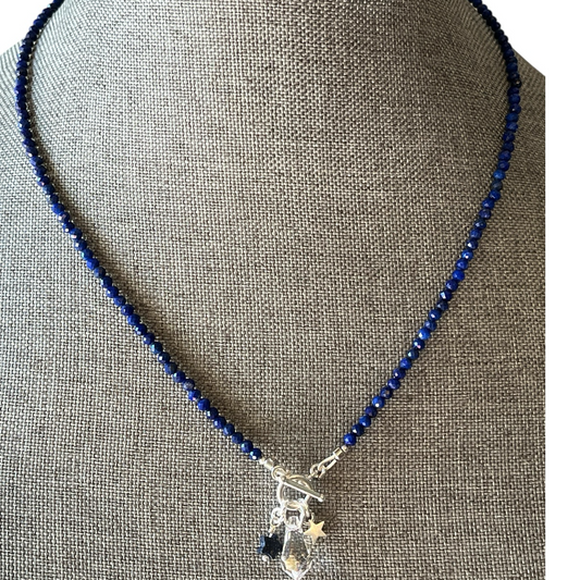 Necklace with blue beads and silver charms on a gray mannequin