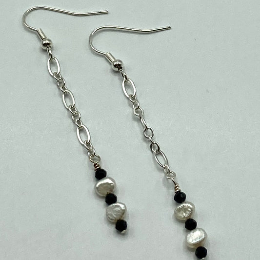 The earrings are approximately 2 inches in length and are made with chain, Black Spinel beads, and small freshwater pearls