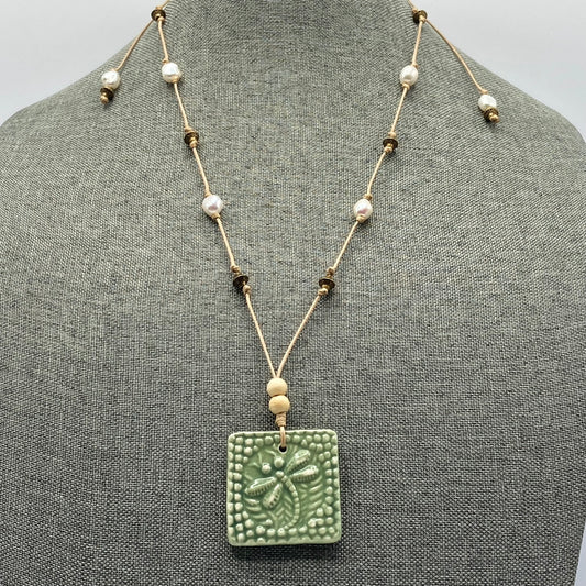 Adjustable hand-knotted pearl necklace with sage-colored ceramic dragonfly pendant.